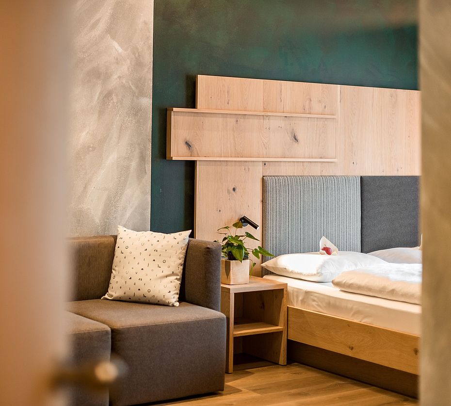 Moderne hotelkamer met grijze gestoffeerde fauteuil en turquoise wandafwerking