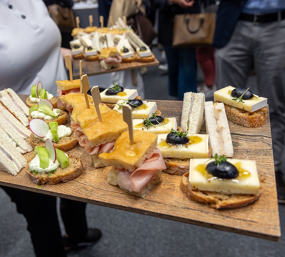 Servicemitarbeiter trägt Holzbrett mit Fingerfood-Häppchen bei Veranstaltung