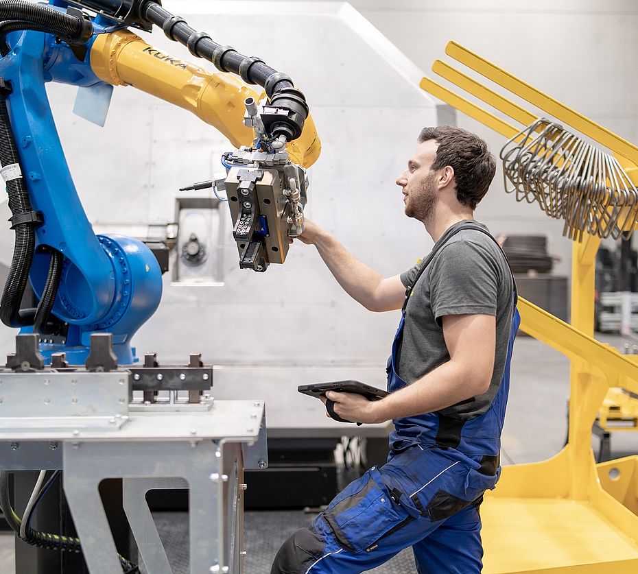Techniker mit Tablet prüft Greifer eines KUKA-Industrieroboters