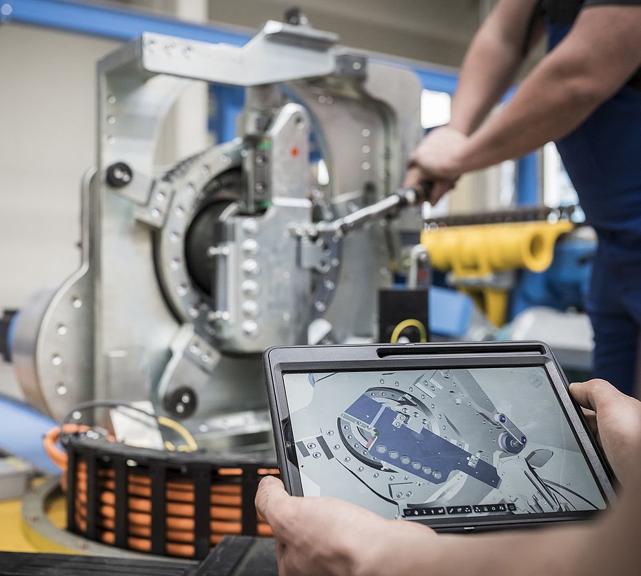 Mitarbeiter mit Tablet neben Kollegen an Industriemaschine